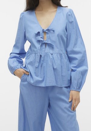 Light blue, long-sleeve top with a deep V-neck, tie detail at the bust, and a peplum hem. Vertical white stripes and textured fabric.