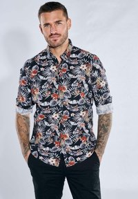 Kurzarmhemd aus schwarzem Stoff mit einem bunten Blumen- und Blattmuster, mit umgeschlagenen Ärmeln und einer Knopfleiste.