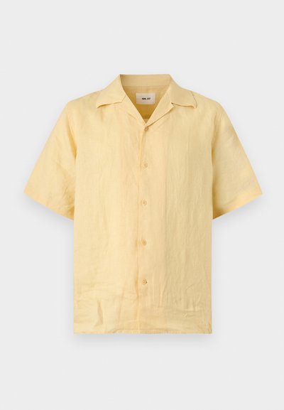 Chemise à manches courtes, boutonnée, jaune clair avec un col camp, faite dans un tissu léger légèrement texturé.