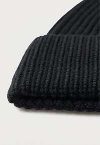 Gorro de punto negro con costillas y borde doblado. El material parece suave y con textura, con estrías verticales uniformemente espaciadas.