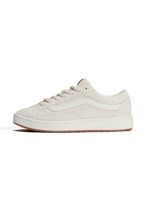 Zapatilla baja de ante beige con franja lateral blanca, cierre de cordones y suela blanca con dibujo marrón claro, mostrada de perfil.