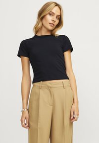 Zwarte cropped t-shirt met korte mouwen van gladde katoen, gecombineerd met beige broek met hoge taille, plooien en zijzakken.