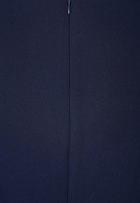 Tissu bleu foncé avec une couture verticale au centre et une petite tirette métallique en haut du bord.