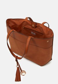 Brun läder toteväska med två handtag, innerväska och detaljer i guld. Inkluderar en tofs och logocharm.