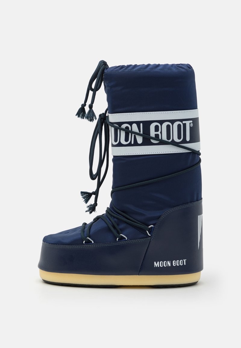 Sötétkék Moon Boot párnázott kialakítással, logós szalaggal, fűzős részletekkel és bojtokkal, valamint gumitalppal.