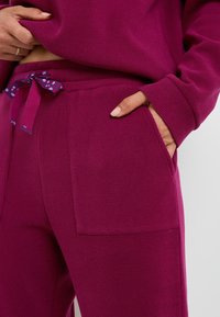 Ensemble de loungewear fuchsia en tissu texturé. Comprend une taille avec un lien à motif et des poches latérales pour plus de fonctionnalité.