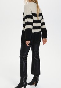 Mustat ja kerma-valkoiset raidalliset villapaidat, jotka on valmistettu pehmeästä langasta. Niissä on löysä istuvuus, ribattu hihansuu ja korkeammalle takaa ulottuva helma. Paita on yhdistetty nahkahousuihin ja saappaisiin.