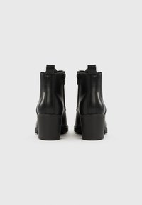 Czarne skórzane botki za kostkę o gładkiej fakturze, z bocznymi zamkami i masywnym obcasem. Prosty design z zaokrąglonym noskiem i tylną pętelką ułatwiającą zakładanie.