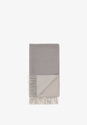 Couverture grise avec un dessous gris clair, présentant des bords frangés et un petit accent doré. Texture lisse et forme rectangulaire.