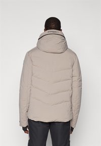 Casaco puffer cinza claro com gola alta e capuz ajustável. Apresenta costuras horizontais e um logótipo perto da gola.