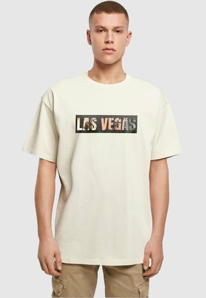 Cremefarvet bomulds T-shirt med oversized pasform, der har en rektangulær grafik med "Las Vegas" i collage-stil på forsiden.