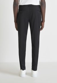 Zwarte broeken met een slim fit, elastische tailleband, twee achterzakken en een gladde textuur, gecombineerd met witte sneakers.