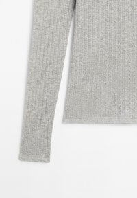 Light gray ribbed long-sleeve shirt with textured vertical lines, shown from the midsection to the end of one sleeve on a white background.