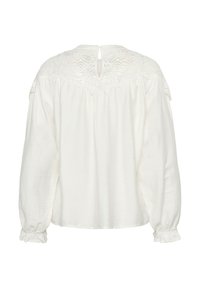 Blusa bianca con maniche lunghe, in tessuto testurizzato, con dettagli in pizzo sulle spalle e chiusura a chiave sul retro. Presenta polsini arricciati.