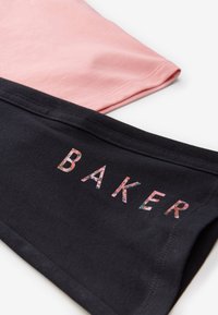 Lag af sort og pink bomuldsstof; det øverste stykke i pink er glat; det nederste sorte stykke har blomster og bogstaverne "BAKER" i en tekstureret tryk.