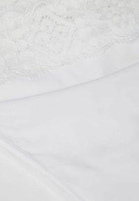 Tissu blanc avec des détails en dentelle complexes en haut, texture lisse et design sans couture. Matériau doux et léger.