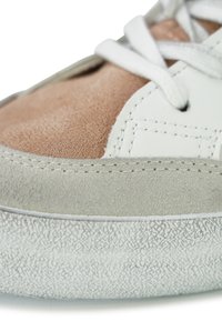 White leather sneaker with pink and grey suede panels. Features textured rubber sole and white laces. Stitching detail visible on edges.