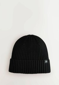 Zwarte gebreide beanie van ribstof, met een omgeslagen rand en een klein logo-patch aan de voorkant.