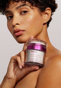 Murad Heartleaf Calming Cream i en klar glasburk med lila lock; har en slät, modern design och minimalistisk märkning.