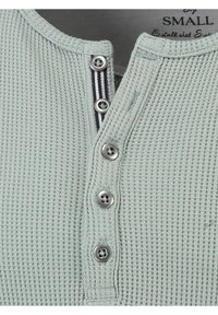 Mintgrünes, strukturiertes Baumwolltop mit Henley-Ausschnitt, vier metallischen Knöpfen und einem marineblauen gestreiften Akzent an der Knopfleiste. Größe klein.