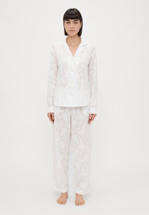 Biele, ľahké pyžamo pozostávajúce z goliera, košele na gombíky a voľných nohavíc s jemným kvetinovým vzorom. Mäkká textúra.
