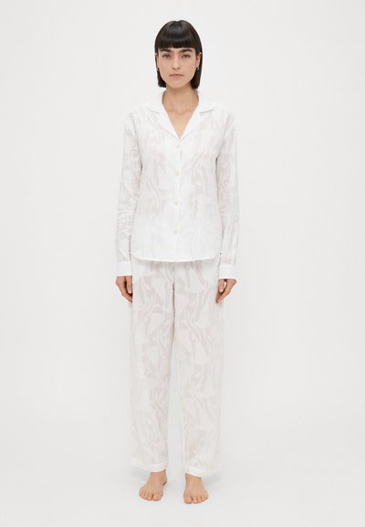 Set di pigiama bianco e leggero composto da una camicia colletto con bottoni e pantaloni larghi con un motivo floreale discreto. Texture morbida.