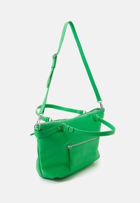 Sac à main en cuir vert avec bandoulière ajustable, poche zippée et texture lisse. Présente une quincaillerie métallique et un design structuré.
