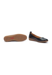 Chaussures plates en cuir noir avec un bout arrondi, semelle en caoutchouc beige et design minimaliste. L'intérieur est beige avec une texture lisse.