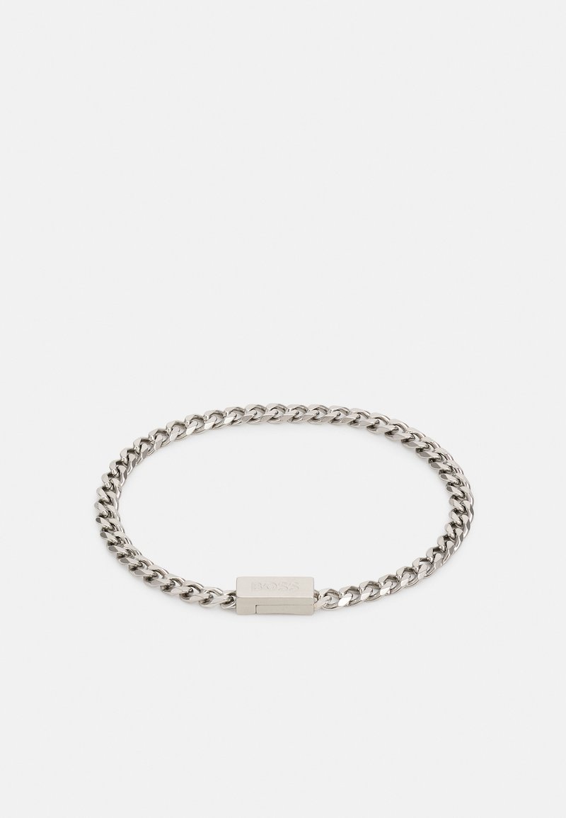 Bracciale in metallo argentato con chiusura rettangolare piatta, caratterizzato da una superficie liscia e un design intrecciato. Accentuato da un'incisione del marchio.