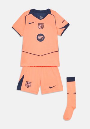 Completo da calcio arancione con accenti blu navy, composto da una maglia a maniche corte, pantaloni corti e calze al ginocchio, contrassegnato dai loghi Nike e FC Barcelona.