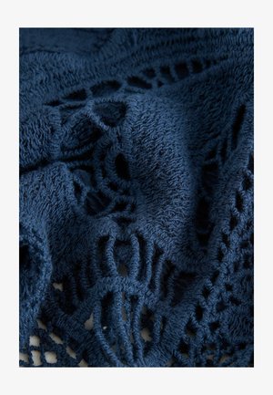 Mørkeblå struktureret stof med indviklede blonde mønstre og frynsede kanter, der fremhæver et blødt, vævet udseende.