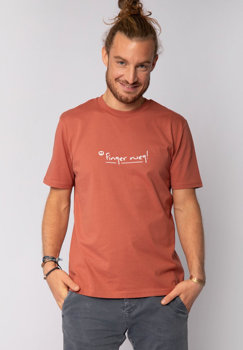 Rostfarbendes Baumwoll-T-Shirt mit kurzen Ärmeln und Rundhalsausschnitt; mit weißem Text "Finger weg!" auf der Brust bedruckt.