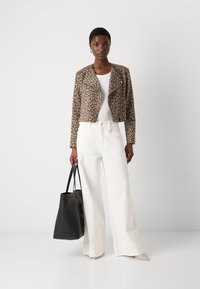 Luipaardprint, cropped jas in beige en bruine stof; gecombineerd met witte, wijde broek en een zwarte handtas, afgewerkt met nude hakken.