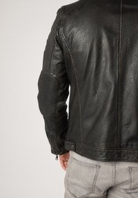 Schwarze Leder-Motorradjacke mit gerippten Schulter- und Ellenbogenakzenten, Reißverschlussärmeln und einer leicht abgenutzten Textur.