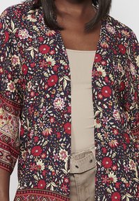 Kimonojas met bloemenprint in marineblauw met rode en roze bloemen, voorzien van 3/4 mouwen en ingewikkelde patroonaccenten langs de zoom.