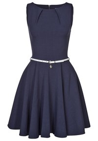 Robe bleu marine avec un design sans manches, un corsage ajusté, des plis au niveau du col et une ceinture blanche avec une boucle métallique. Jupe évasée.