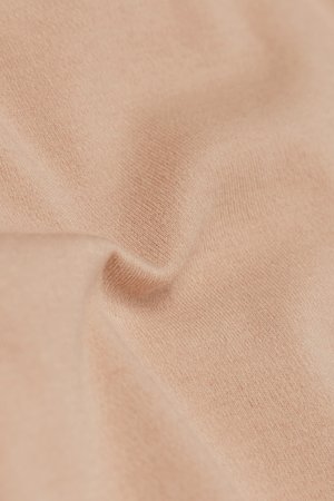 Tela suave de tono beige claro con textura de punto visible y pliegues sutiles que muestran arrugas suaves y caídas delicadas.