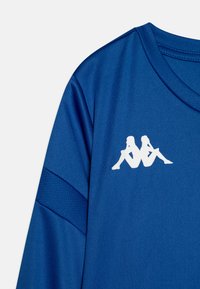Modra športna majica iz gladkega materiala, z belim logotipom, na katerem sta upodobljena dva silhuetna lika, ter strukturiranimi poudarki na rokavu.