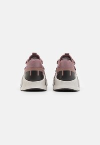 Paarse textielsneakers met zwarte accenten en een witte zool. Beschikt over een uniek achterontwerp met gebogen lijnen op de hak.