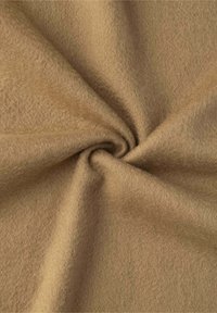 Tessuto di lana beige, dalla texture morbida, superficie leggermente pelosa, disposto in un arrangemento a spirale, che mette in evidenza una ricca tonalità di marrone con leggere variazioni.