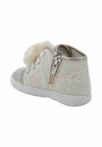 Sneaker alta in tessuto beige testurizzato con pom-pom soffice, lacci bianchi, cerniera laterale e suola in gomma bianca.