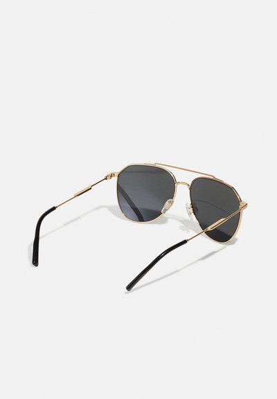 Kultaiset metalliset lentäjäsunglasses, joissa on oktaalimuotoiset linssit, tummanharmaa sävy ja mustat muoviset tempurit. Mukana on läpinäkyvät silikoniset nenätyynyt.