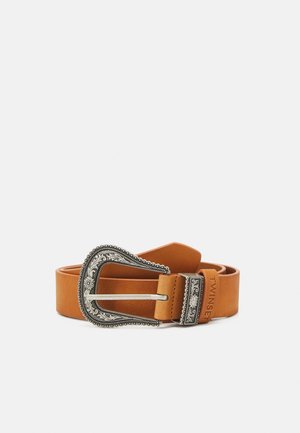 Jasnobrązowy pasek ze skóry z wygrawerowaną srebrną sprzączką i dopasowaną pętlą, zwinięty i oparty o jednolite jasne tło.