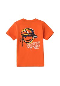 Camiseta de algodón naranja con un gráfico de una cara sonriente con una gorra, acompañada del texto "STREET BALL" y detalles de goteo de pintura coloridos.