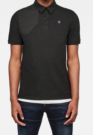 Polo nero realizzato in cotone con un pannello texture sulle spalle e colletto con bottoni. Presenta un piccolo logo sul petto.