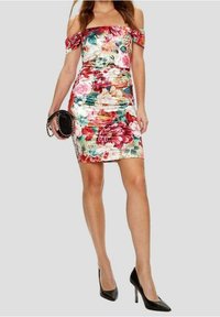 Robe fleurie décolletée avec des motifs vibrants roses, rouges et verts, coupe slim, longueur au genou, tissu lisse. Talons hauts noirs et pochette.