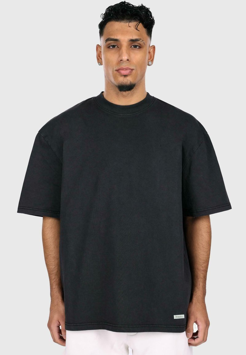 Camiseta negra de gran tamaño hecha de algodón, con un cuello redondo y mangas cortas, con detalles de costura sutil y una etiqueta de logo en el dobladillo.