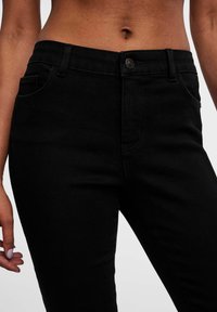 Jeans en denim noir au design slim, dotés d'une fermeture à bouton, de cinq poches et de détails de couture contrastants.