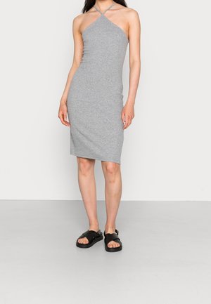 Graues, figurbetontes Neckholderkleid mit dünnen Trägern und knielangem Saum. Modell trägt schwarze Sandalen mit flacher Sohle. Glatter Stofftextur.