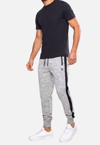 Black crew-neck t-shirt paired with gray joggers featuring a textured surface and black side stripes, completed with white sneakers.